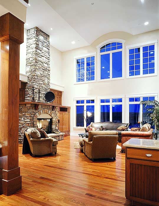 Great room with stone fireplace, vaulted ceiling, and large multi-pane windows.