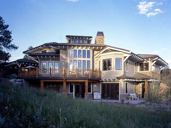 House plan exterior with multiple stories, expansive decks, large windows, gabled roofs, and stone accents.