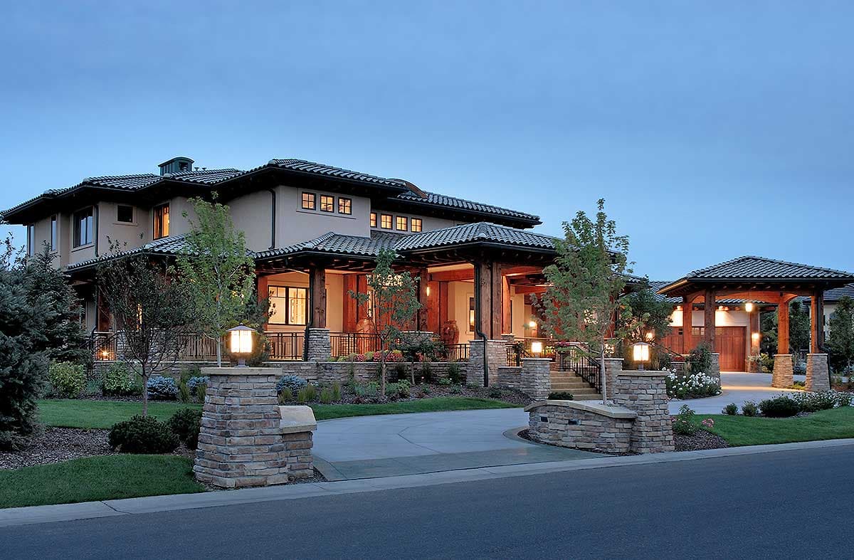 House plan exterior of a two-story home with a covered porch, large windows, stone pillars, and a detached garage.