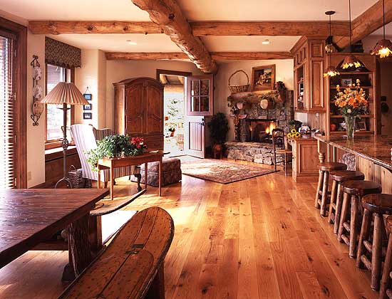 Open-concept living space with a stone fireplace, wood-beamed ceiling, and a kitchen island with bar stools.