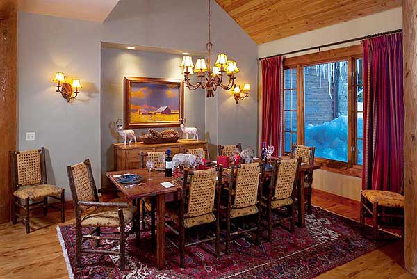 Dining room with rustic wood table and chairs, large window, and vaulted wood ceiling.