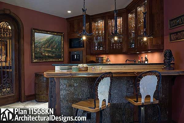 Custom bar with wood slab countertop, wood cabinetry with glass doors, and bar stools with hide upholstery.