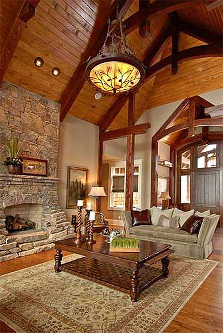 Great room with stone fireplace, vaulted wood-beam ceiling, chandelier, sofa, and coffee table.