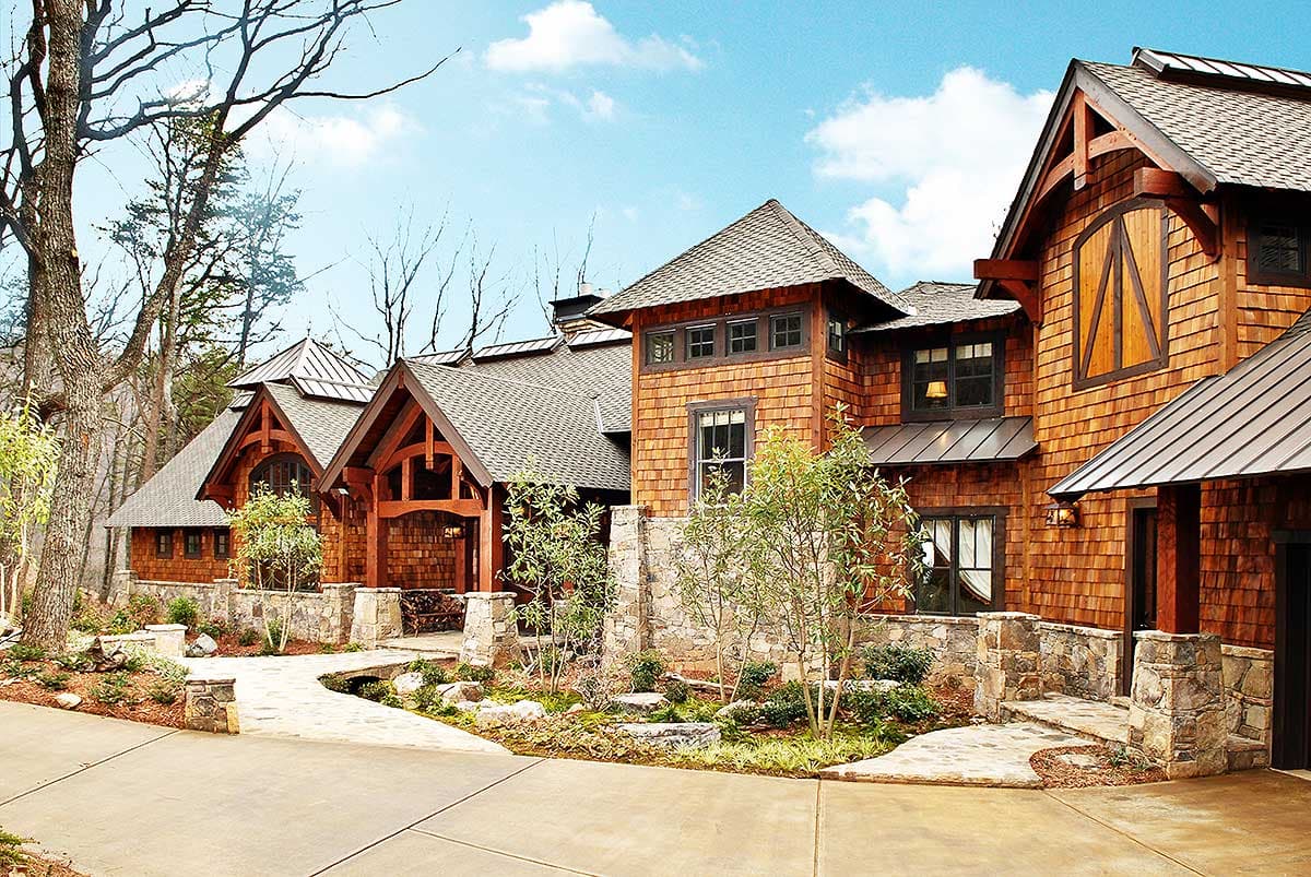 House plan exterior featuring wood shake siding, stone accents, prominent gables, and covered entryway.