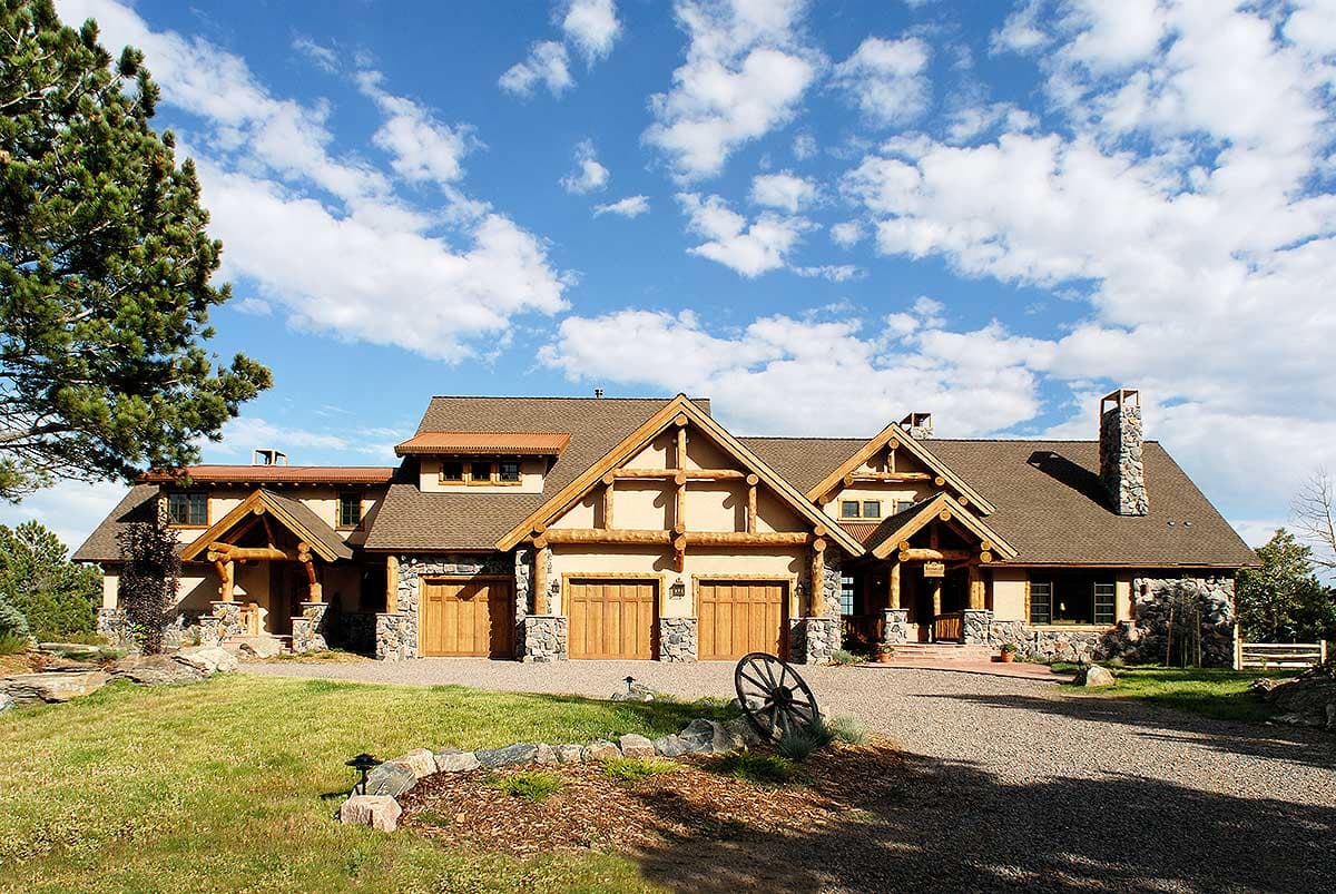Log and stone house plan exterior with a prominent A-frame gable, three-car garage, and covered entry.