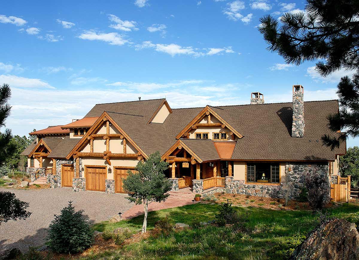 Log home exterior with timber framing, stone accents, multiple gables, and a three-car garage.