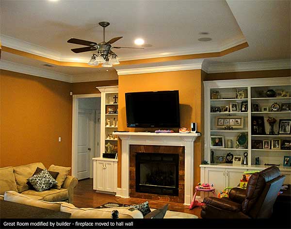 Great Room with fireplace, built-in bookshelves, ceiling fan, and tray ceiling. Sofa and recliner visible.