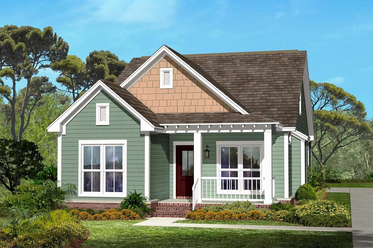 A craftsman-style house with green siding, a brown roof, and a red front door is surrounded by trees and landscaping under a clear sky.