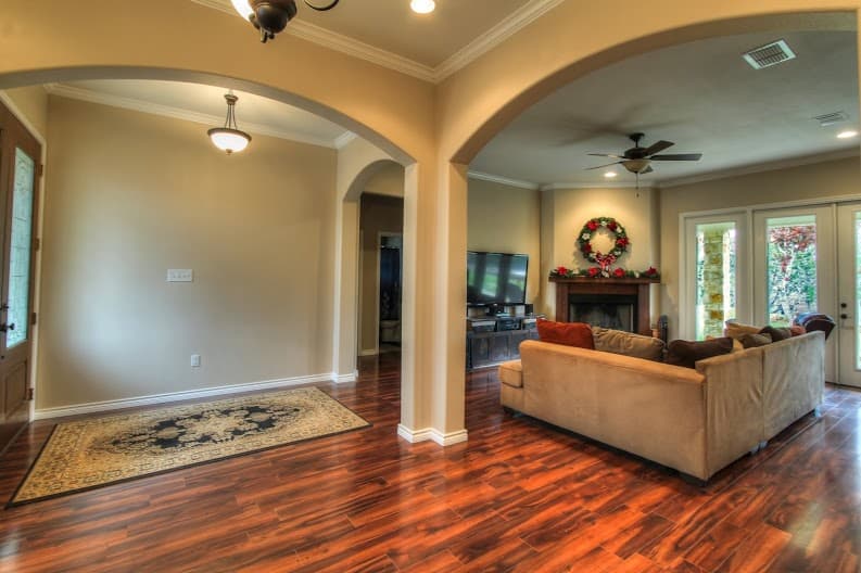 Interior view of a living room with a fireplace, television, couch, arched doorways, and wood flooring.