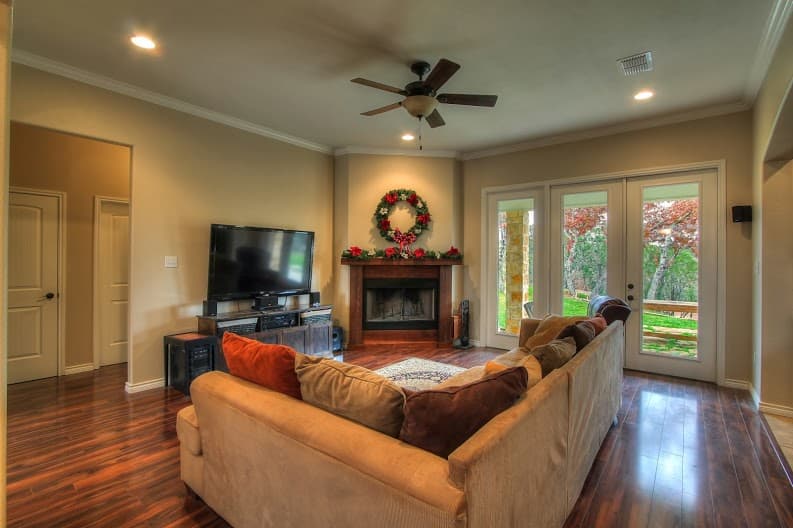Living room with fireplace, television, sectional sofa, and french doors leading outdoors.