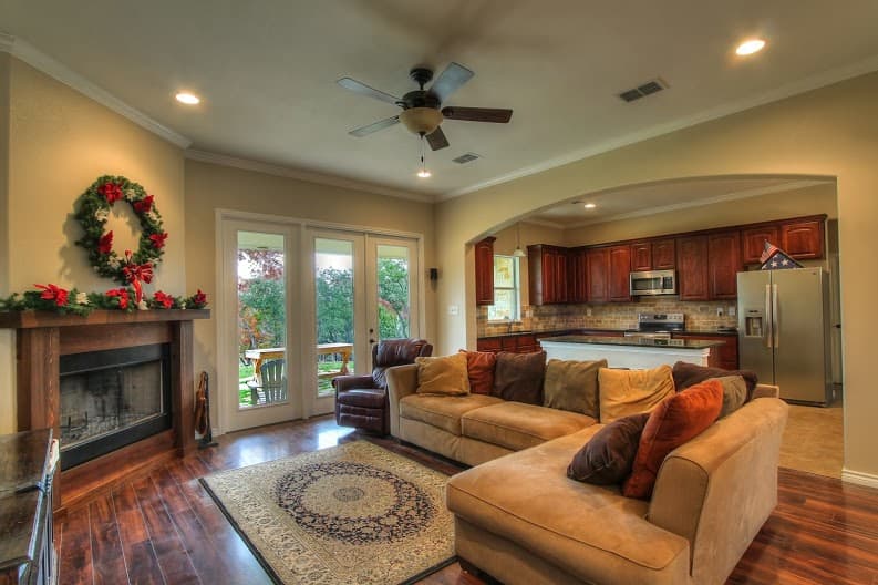 Living room with fireplace, sectional sofa, and open-concept kitchen with island and dark wood cabinets.