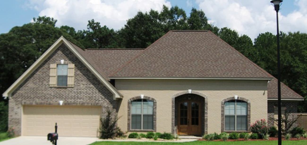 House plan exterior: One-story home with brick accents, garage, arched entry, and gable dormer.