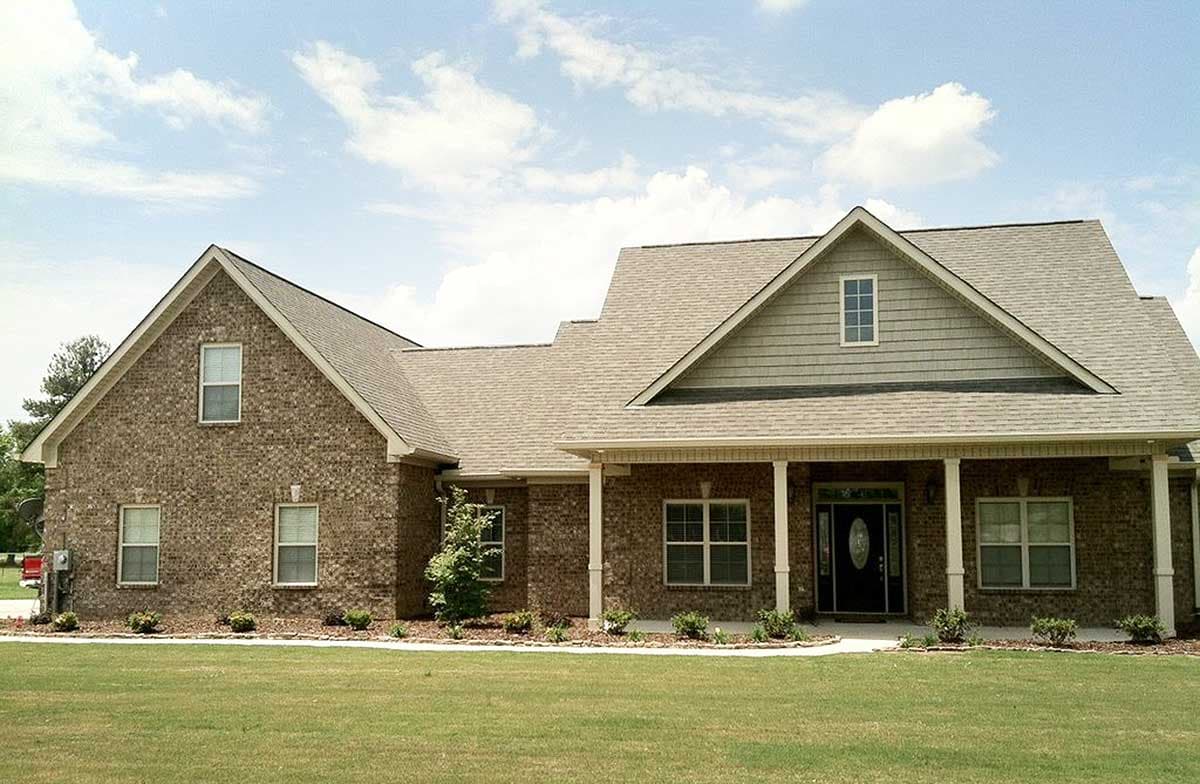 House plan exterior featuring brick facade, covered porch with columns, multiple gables, and a dormer.