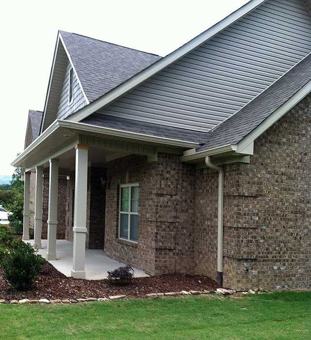 House plan exterior with brick facade, covered porch supported by white columns, and multiple gables.
