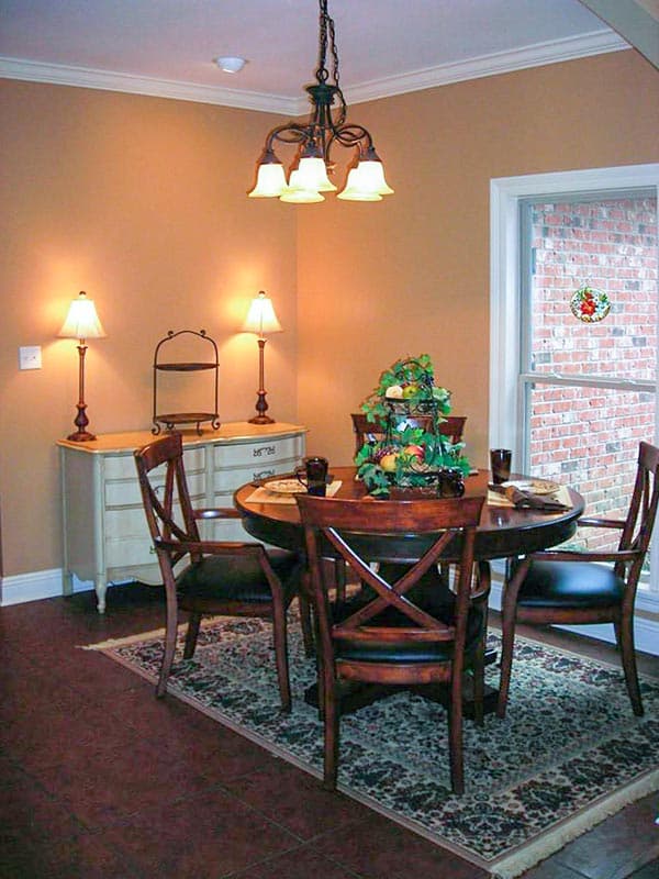 Dining room interior featuring a round wood table with chairs, buffet, and chandelier.