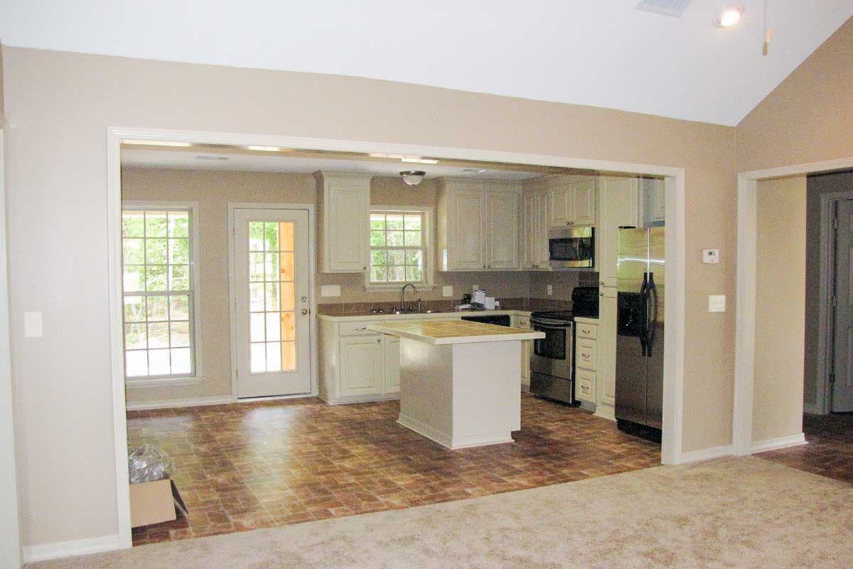Kitchen with an island, stainless steel appliances, white cabinetry, and a door leading outside.