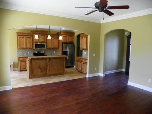 Open concept living area connecting to a kitchen with wood cabinets, a center island, and pendant lights.