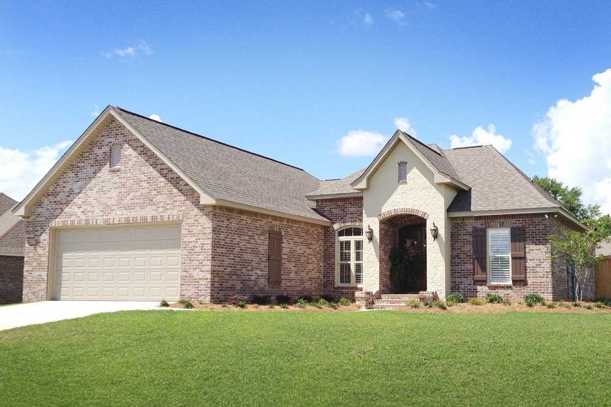 House plan exterior. One-story brick home with attached garage, arched entryway, and gable dormers.