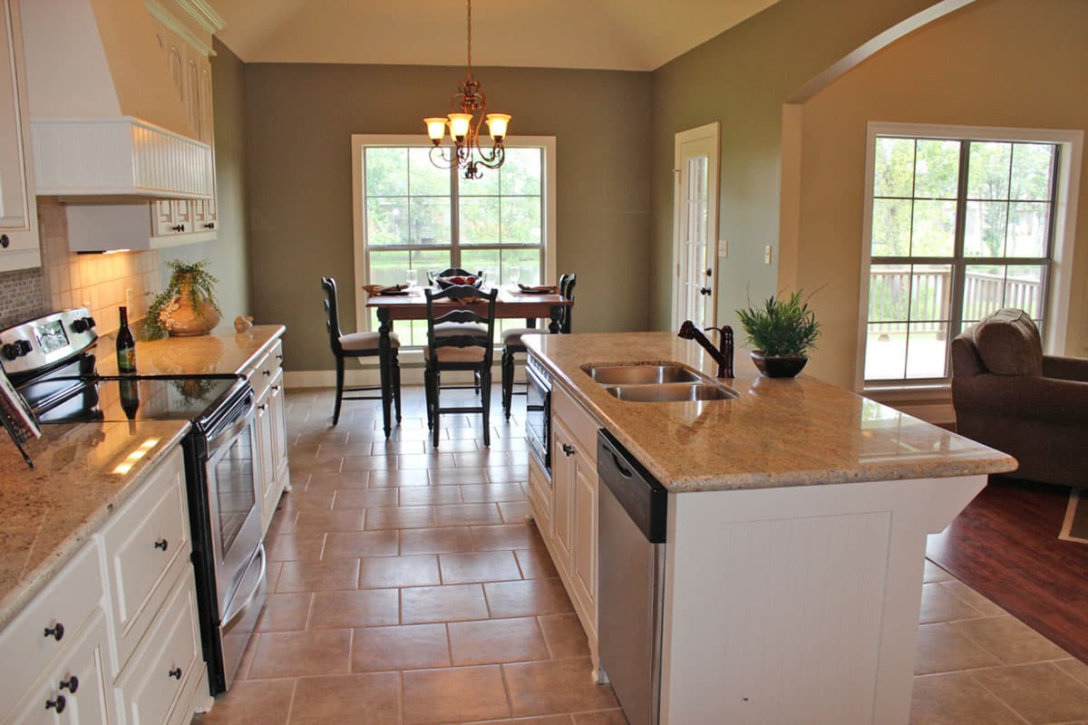 Open-concept kitchen with granite island, stainless steel appliances, dining area, and large windows overlooking a deck.