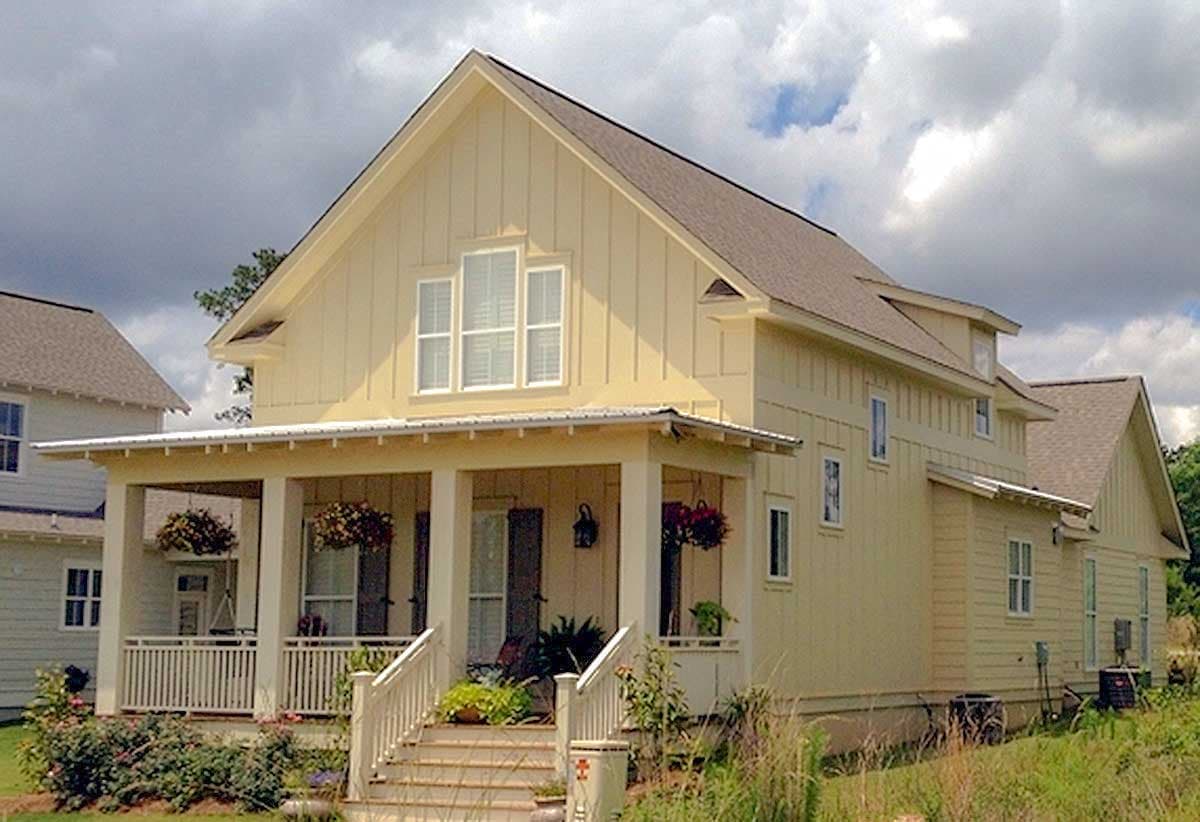 House plan exterior: two-story, light yellow siding, metal roof porch, gables, and dormers.
