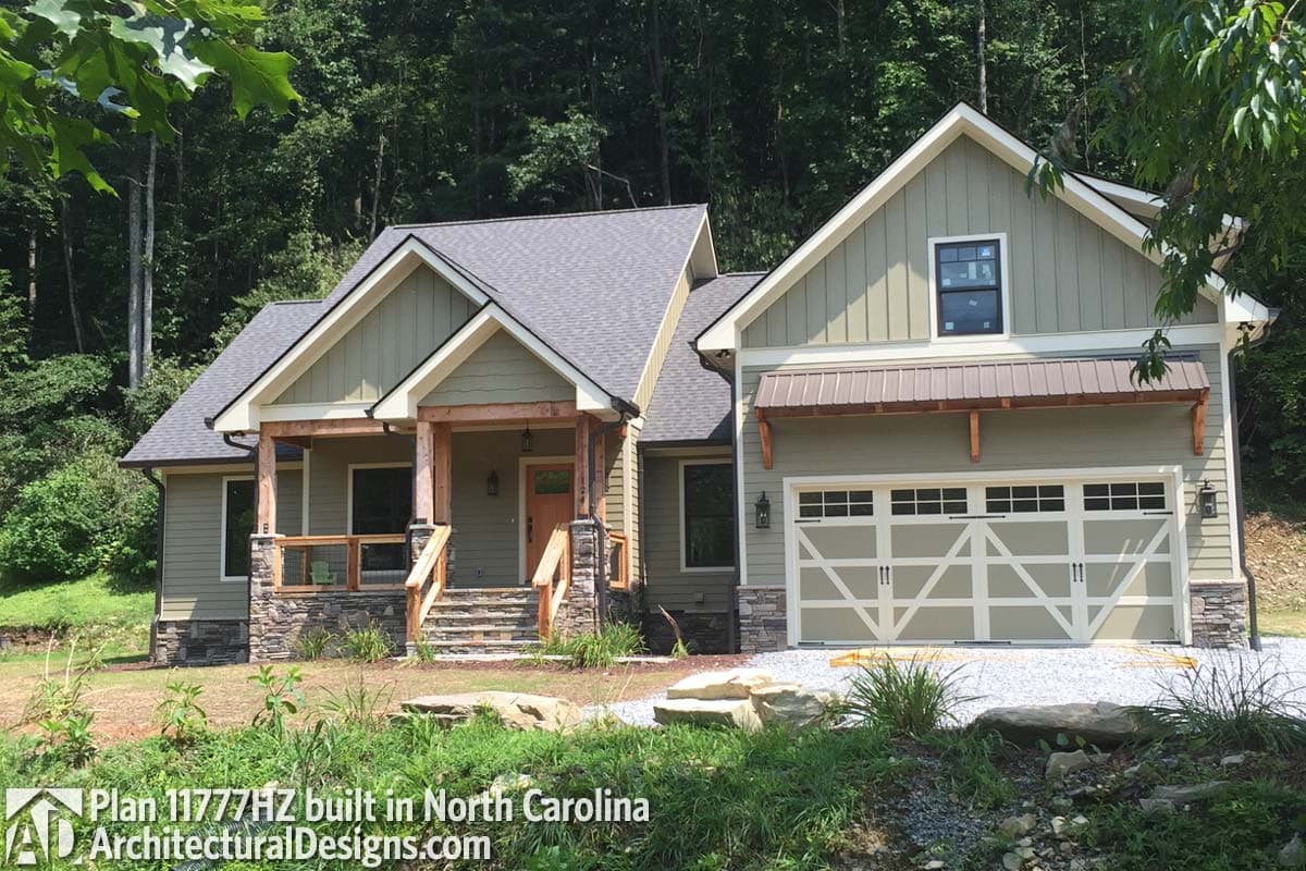 House plan exterior with gabled roof, covered porch with stone base, and side-entry garage with metal awning.
