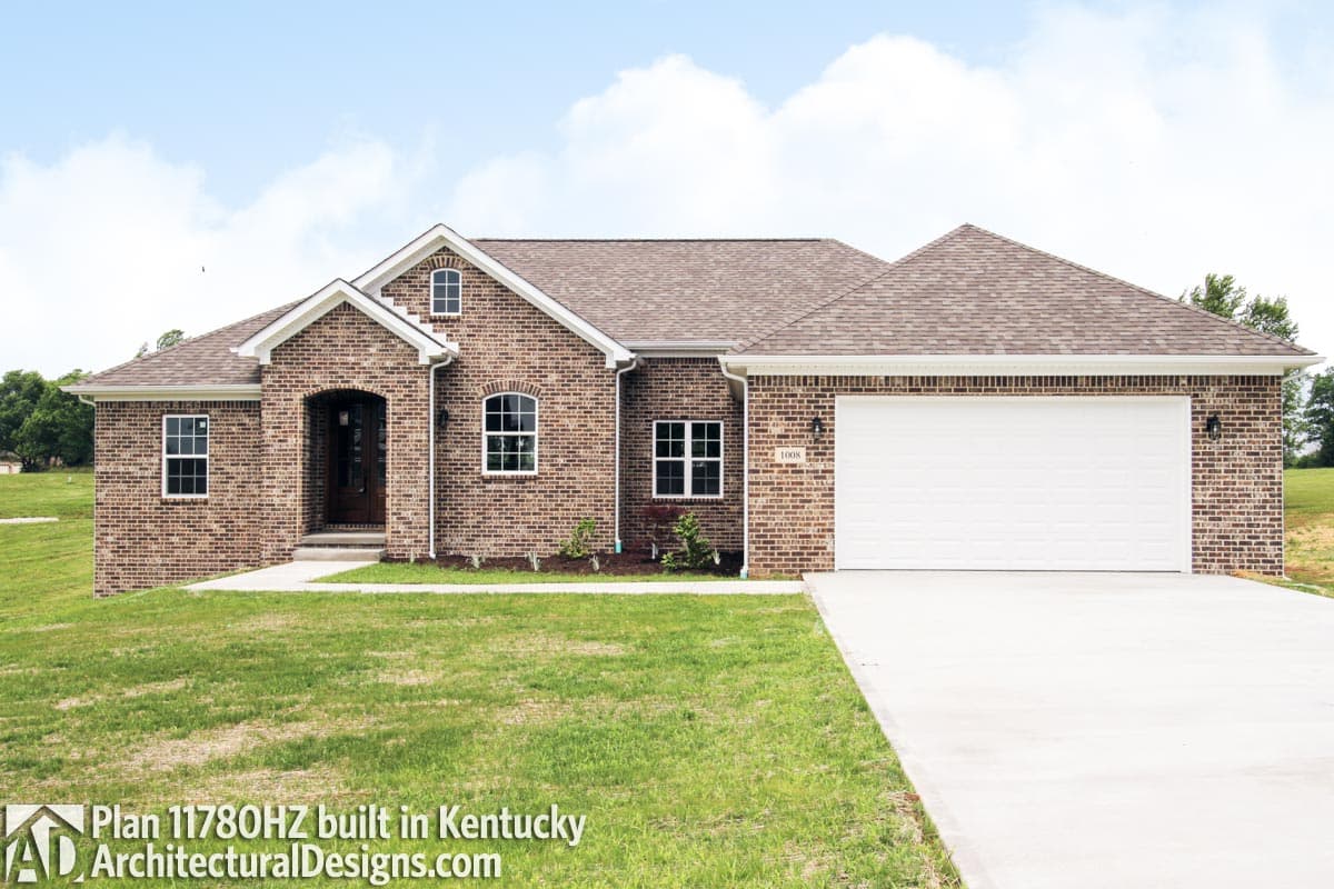 House plan exterior: One-story brick home with arched entry, gabled dormer, and attached garage.