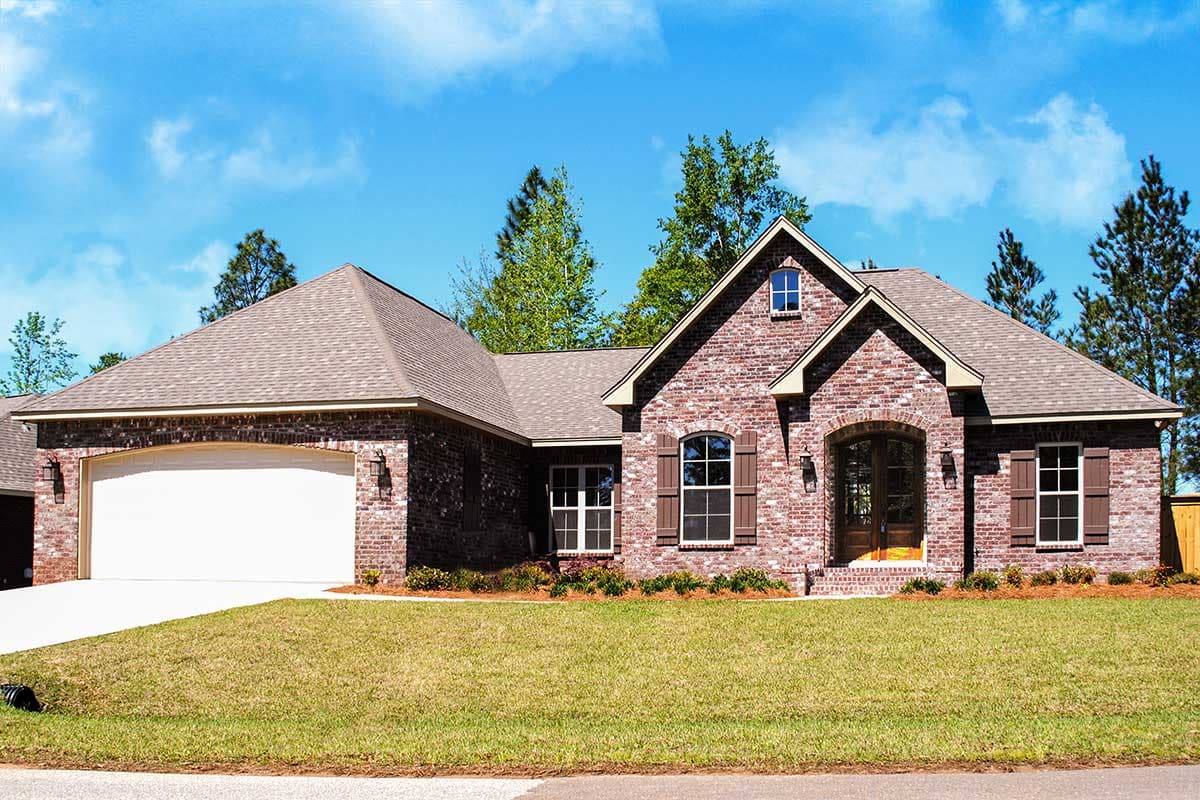 House plan exterior with brick facade, arched entryway, gable dormer, and attached two-car garage.