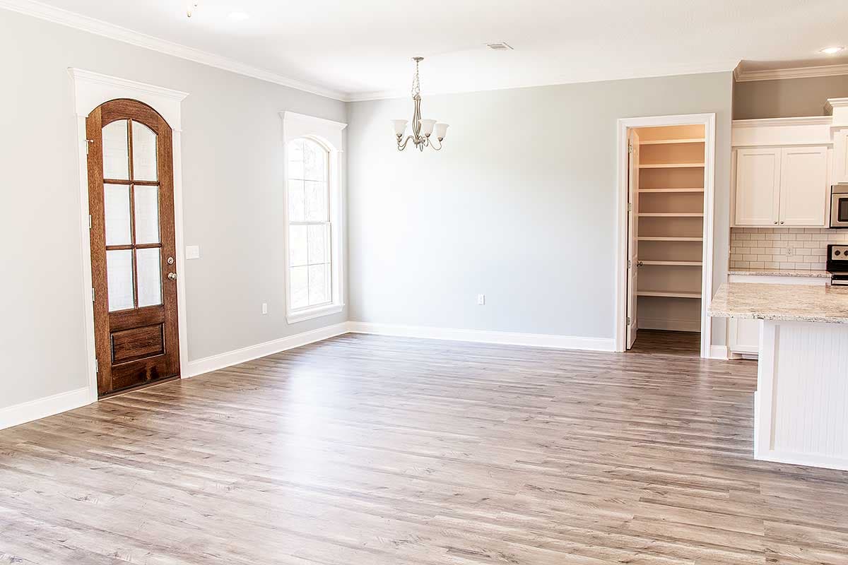 Interior view of a house with a wood door, arched window, pantry, and kitchen island.