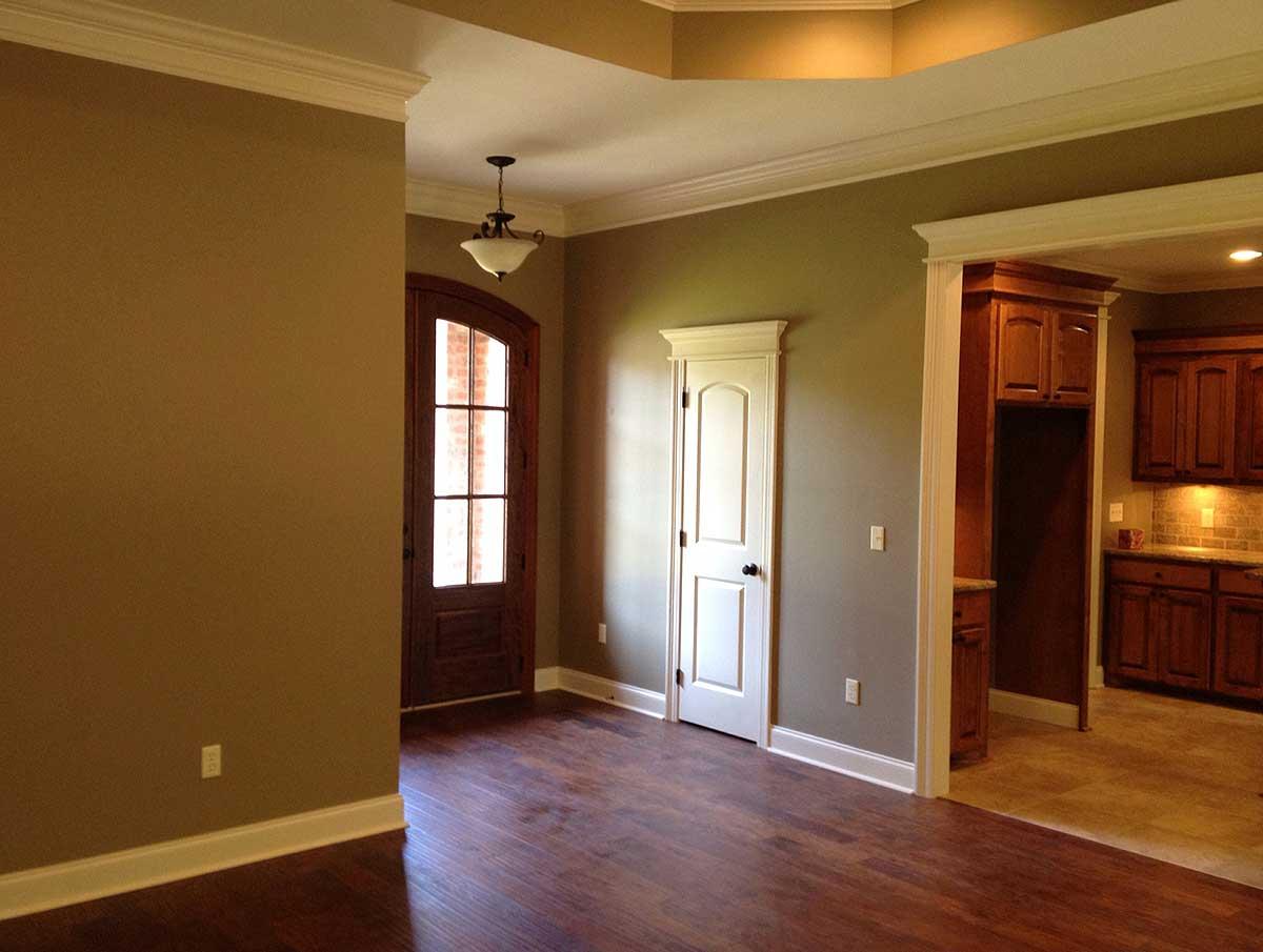 Interior view showing an arched wooden door, a closet door, and a partial view of a kitchen with wood cabinets.