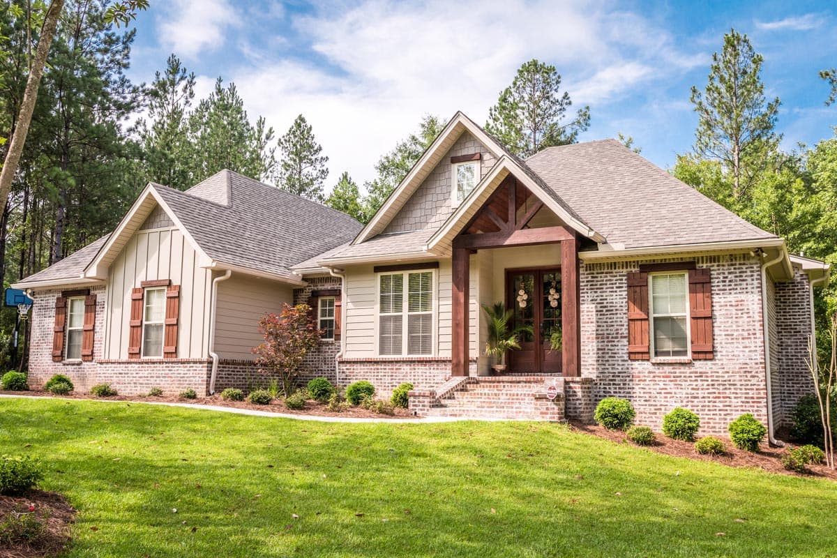 House plan exterior featuring a two-story home with a gabled roof, brick facade, and covered porch with exposed beams.