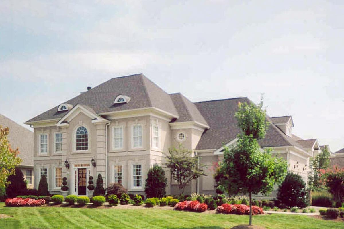 House plan exterior: Two-story home with arched entryway window, multiple dormers, and detailed facade.