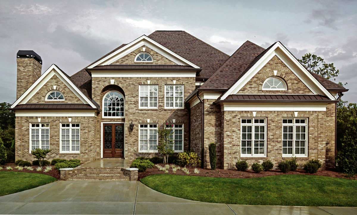 House plan exterior: Brick two-story home with arched entryway, multiple gables, dormers, and a prominent chimney.