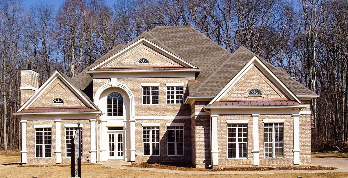House plan exterior: Two-story brick home with arched entryway, multiple gables, dormers, and decorative window trim.