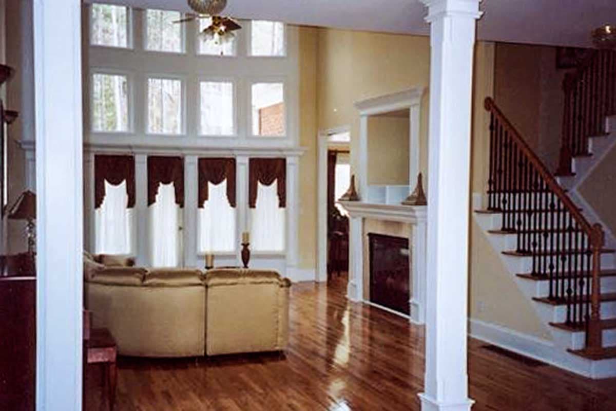 Great room interior with a curved sofa, fireplace, and staircase featuring a dark railing.
