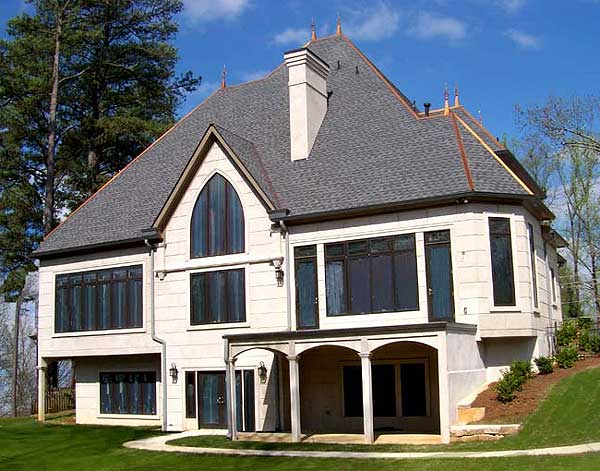 House plan exterior with a prominent arched window, multiple gables, and a covered porch with arched openings.
