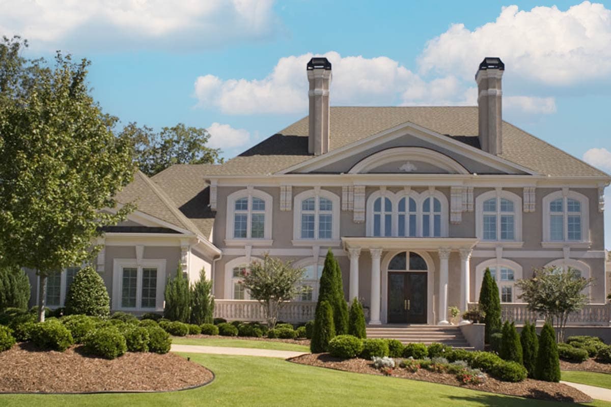 House plan exterior of a two-story house with arched windows, prominent chimneys, and a central portico with columns.