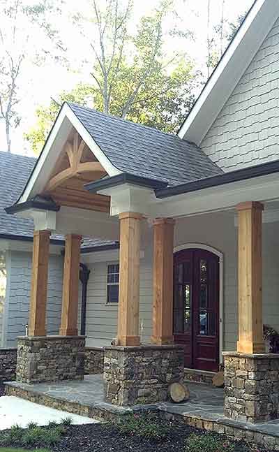 House plan exterior with stone bases, timber columns, arched gable, and double-door entry.
