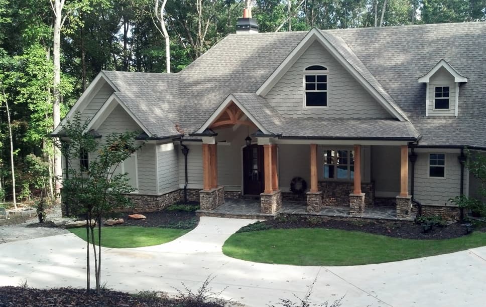 House plan exterior: Craftsman style, two stories, covered front porch with stone and wood columns, multiple gables, and dormer.
