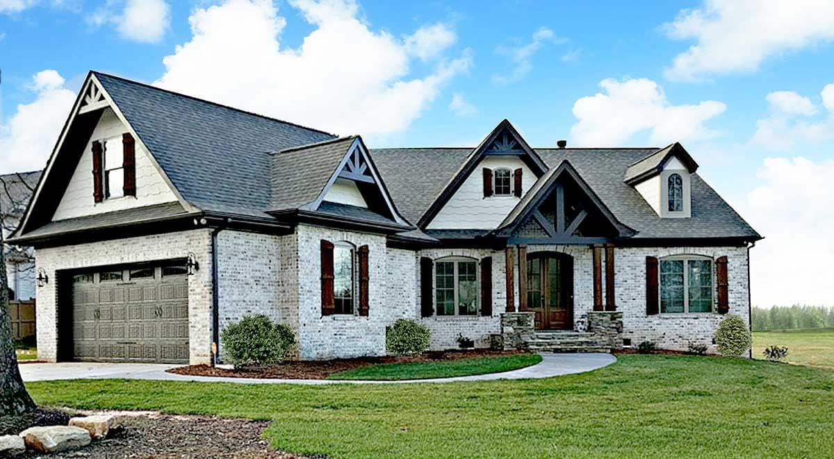 House plan exterior with Craftsman style. Features include gables, dormers, and a brick façade. Two-story with an attached garage.