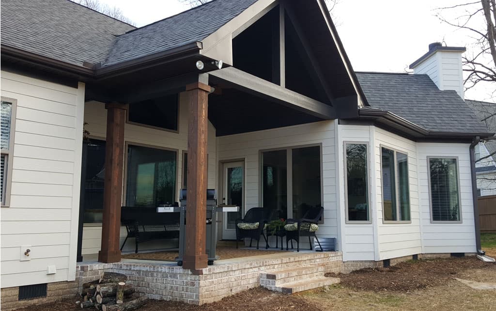 House plan exterior with covered porch, large windows, exposed beams, and gabled roofline.