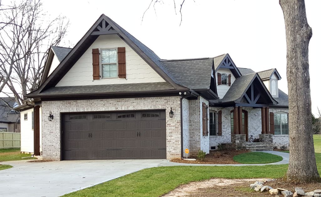 House plan exterior with stone and brick facade, multi-story gables, dormers, and a three-car garage.