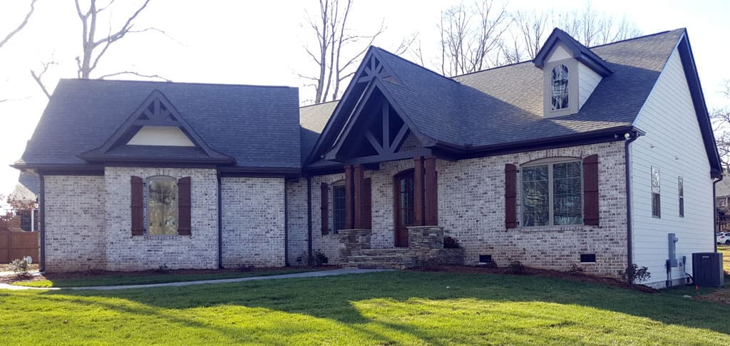 House plan exterior: Craftsman-style, one-and-a-half stories with exposed rafter tails, stone base, and front porch.