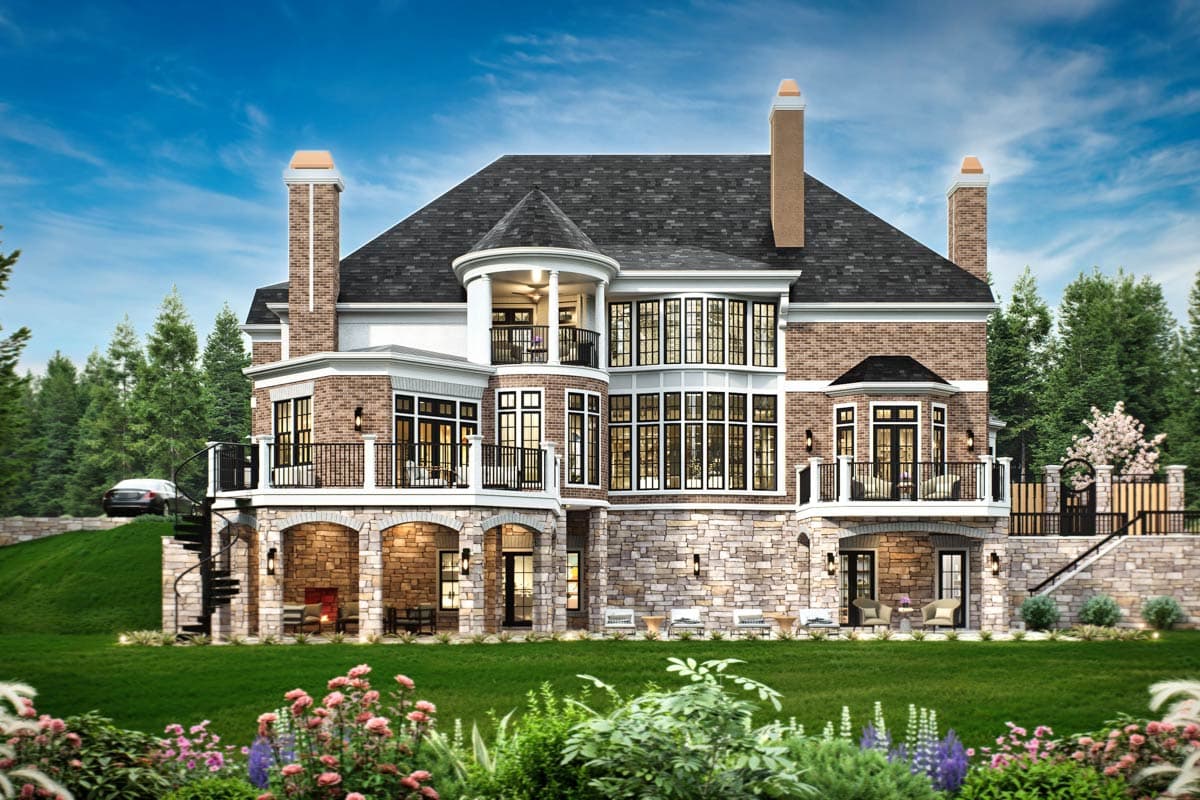 House plan exterior: Traditional brick home with stone accents, multiple balconies, arched openings, and a prominent bay window.
