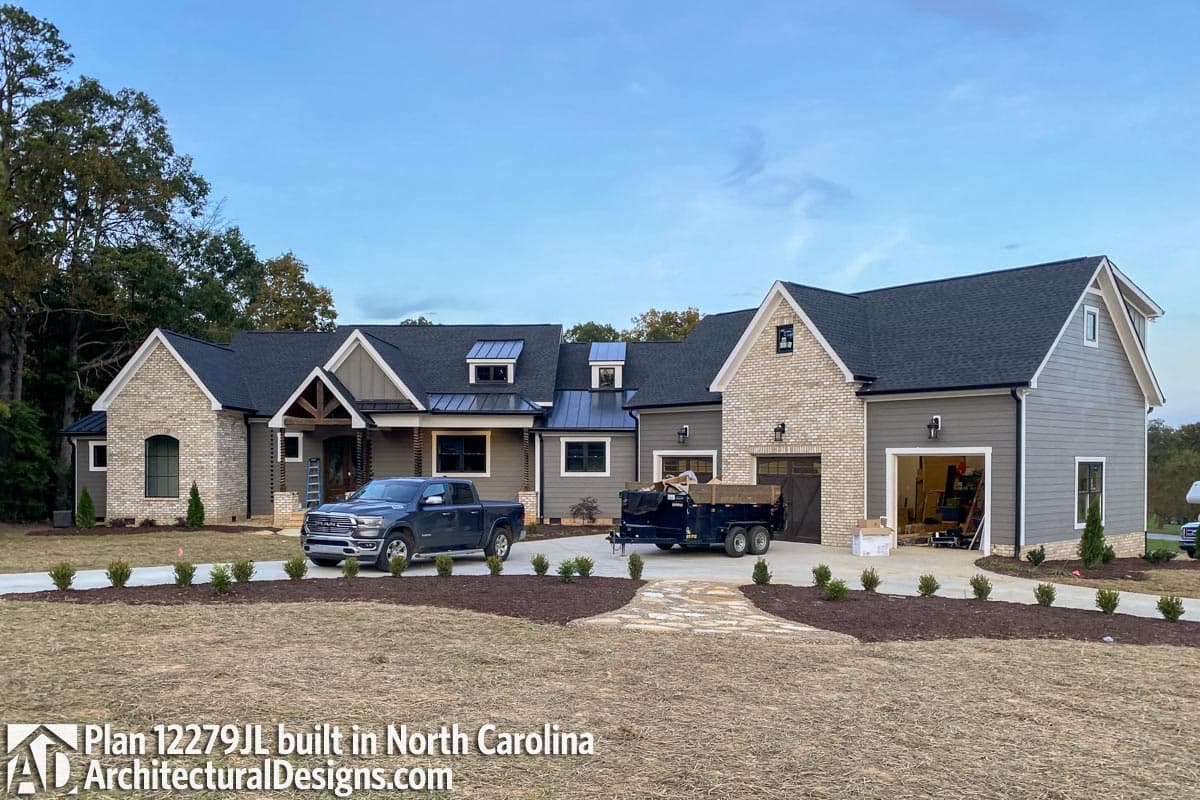 House plan exterior with a mix of stone and siding, gabled roofs, dormers, and a detached garage.