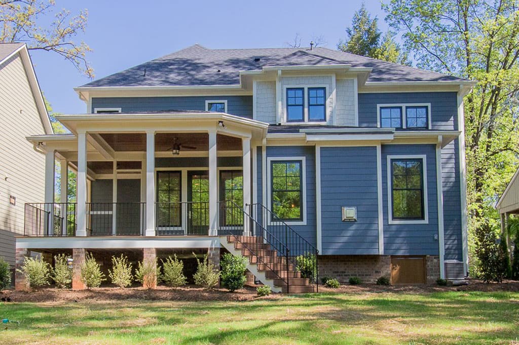 House plan exterior: Two-story home with covered porch, double gables, and visible foundation with brick accents.