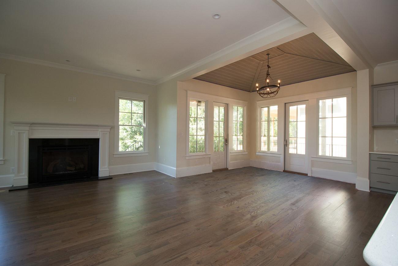 Interior view of a great room with fireplace, French doors, coffered ceiling, and wood flooring.
