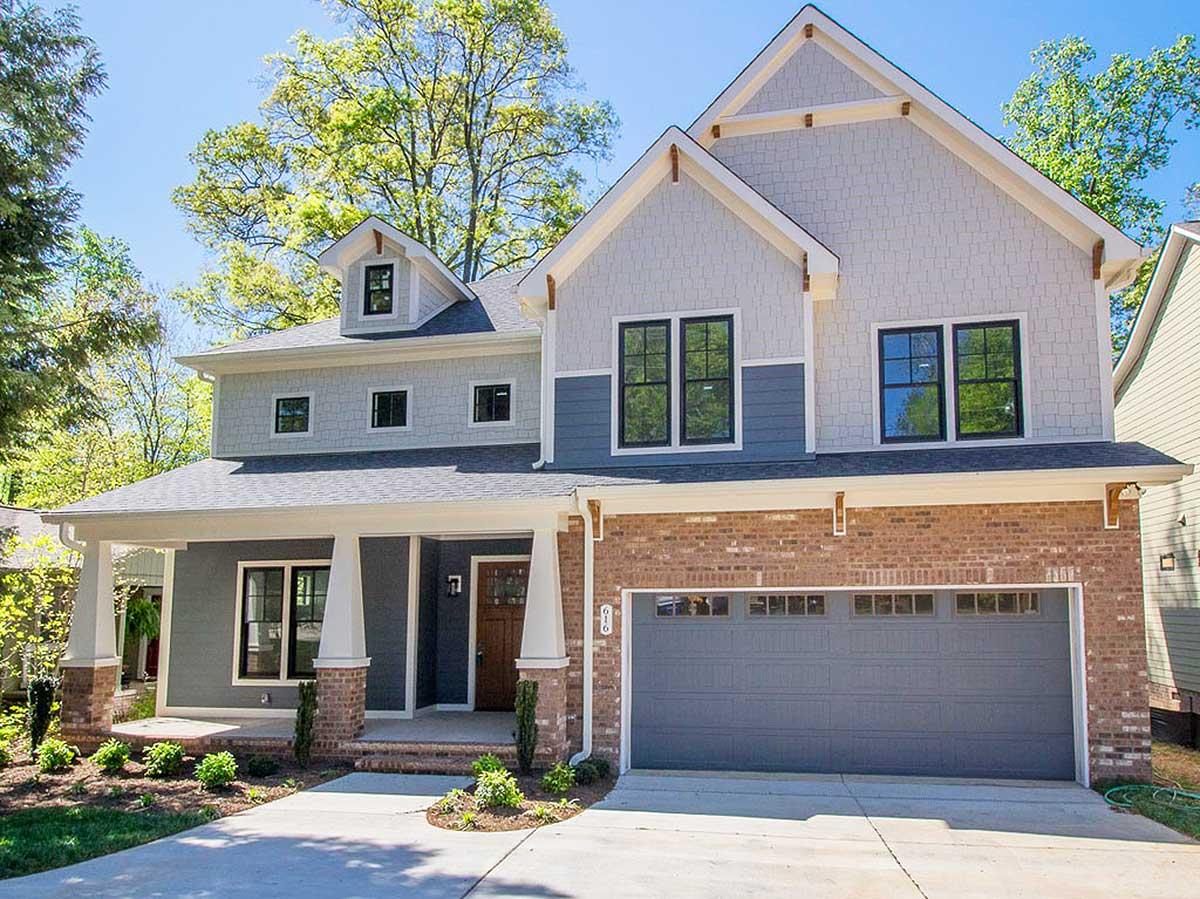 Two-story Modern Farmhouse exterior with brick base, gabled dormer, covered porch supported by stone-clad columns, and a two-car garage.