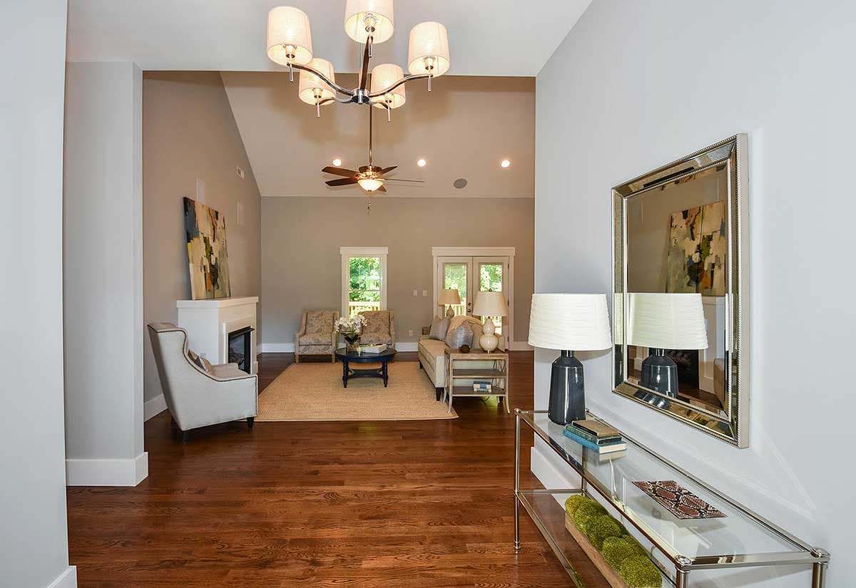 Living room with vaulted ceiling, fireplace, and large windows with double doors leading outside.