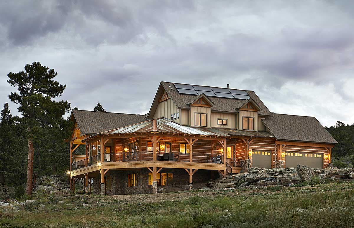 Log and timber house plan exterior with wrap-around porch, solar panels, and a three-car garage.