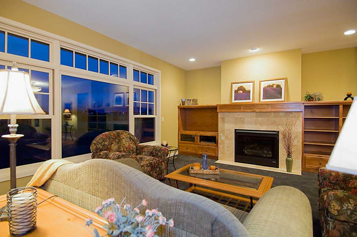 Living room with large windows, fireplace, wood built-ins, and patterned armchair.